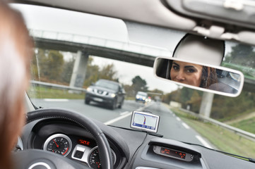 Woman in car binnacle looking at rear view mirror