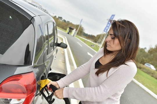 Young Woman Filling Her Car Tank At Gas Station