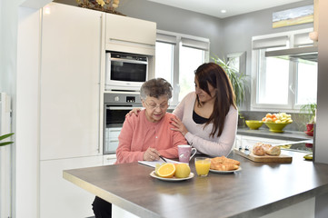 Elderly woman doing crossword while homecare helps at home
