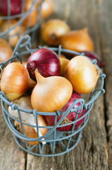 red and yellow onion in an iron basket on wooden surface