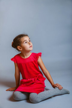 calm girl teenager sits in a red dress looking to the side on