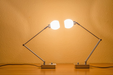 two lit modern lamps looking at each other