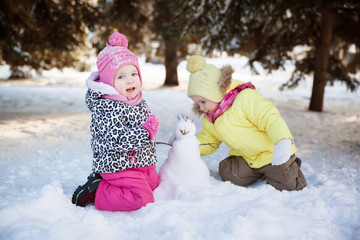 two little girls make a snowman