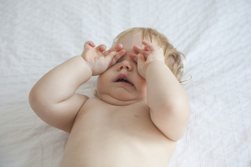 baby yawning on white bed