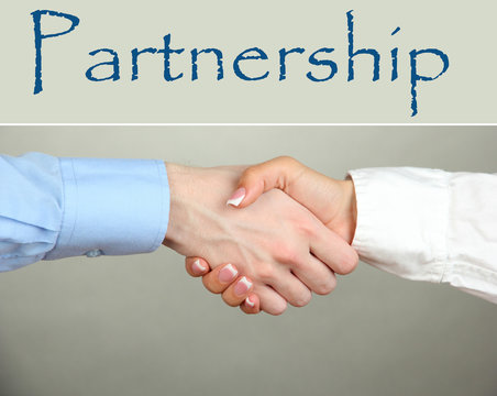 Business handshake symbolizing partnership on gray background
