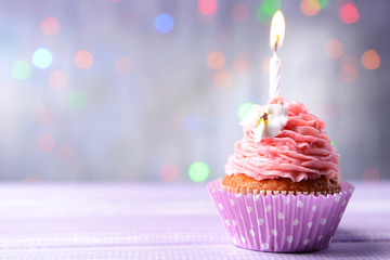 Delicious birthday cupcake on table on light background