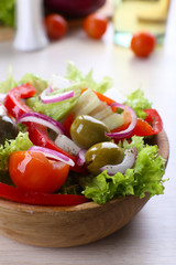 Greek salad in bow on wooden table background