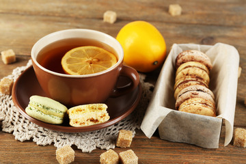 Colorful macaroons with cup of tea on wooden background