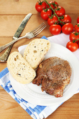 Roasted meat and vegetables on plate, on wooden table