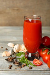 Glass of tasty tomato juice and fresh tomatoes on wooden table