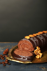 Delicious roll cake on wooden table, on dark background