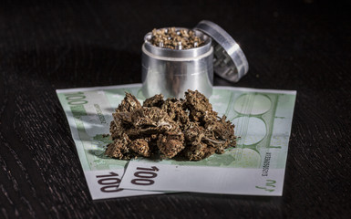 Metal grinder with marijuana and money