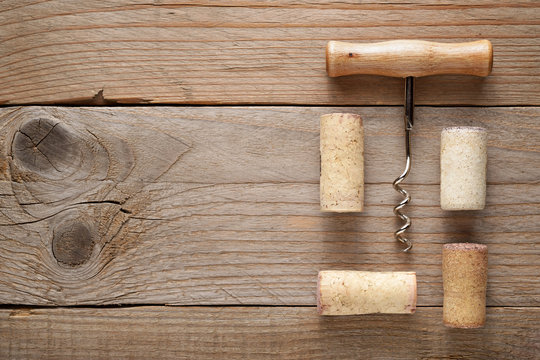 Wine corks and corkscrew on wooden background