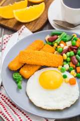 Fish sticks, fried egg and vegetables