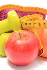 Fruits, tape measure, green dumbbells and towel on white
