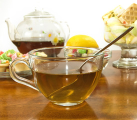 image of a cup of tea, teapot, lemon and cookies closeup
