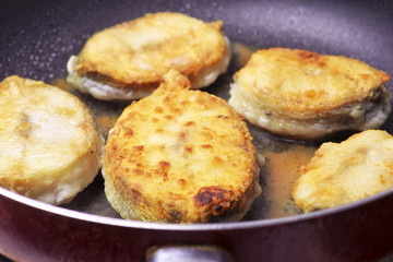Pieces of fried fish in a frying pan with vegetable oil