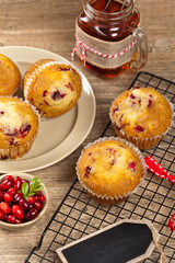 Muffins with cranberry on cooling rack on wooden background.