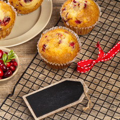 Muffins with cranberry on cooling rack on wooden background.