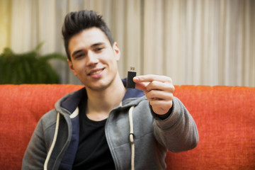 Handsome young man showing USB key in his hand