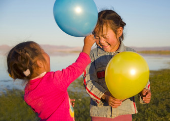 Two Little Girls Playing With Each Other With Balloons