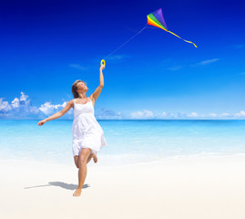 Fototapeta na wymiar Woman Flying a Kite Summer Vacation Beach Concept