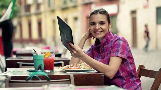 Portrait of happy, young woman with tablet computer in cafe