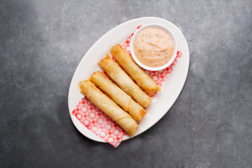 Cheese rolls plate with cocktail sauce served on a wooden plate