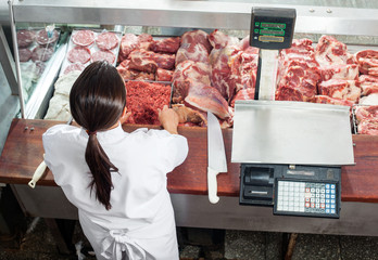 Butcher Working At Display Cabinet In Shop