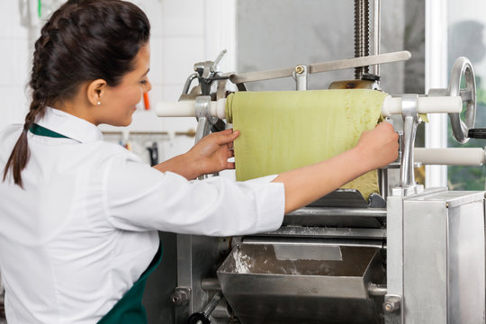Female Chef Processing Ravioli Pasta In Machinery At Kitchen