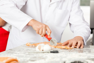 Male Chef Cutting Ravioli Pasta At Messy Counter