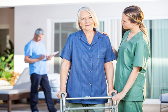Nurse Assisting Senior Woman To Walk With Zimmer Frame