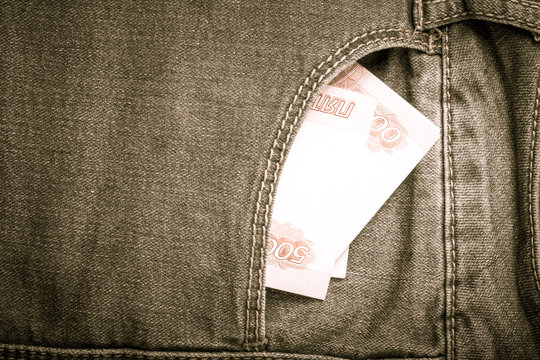 The pocket of jeans with money. Cloth background. Toned