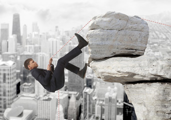 Young businessman scaling a rock