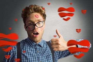 Composite image of geeky hipster covered in kisses