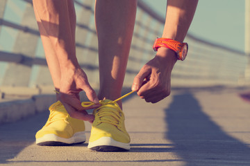 Jogger tying his shoes on a big bridge.