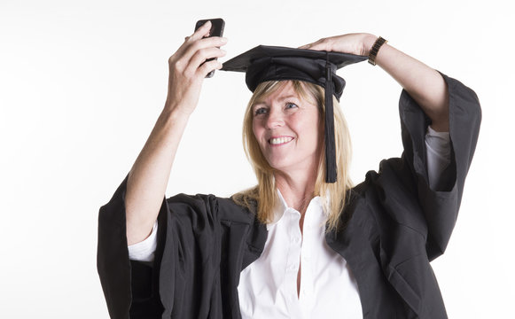 Mature student in cap and gown taking a selfie photo