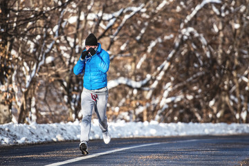 Athletic man running on a forest road and training for sports