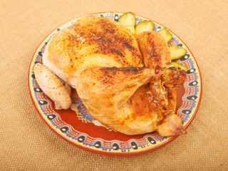 Roasted chicken on a plate with pickles on the canvas.