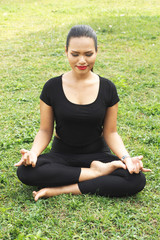 Woman in meditation pose on the green grass