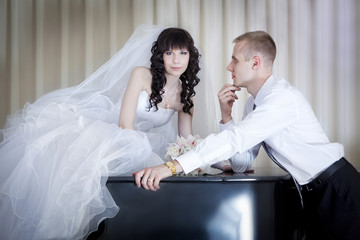 The groom and the bride near a grand piano