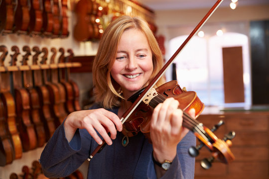 Customer Trying Out Violin In Music Store