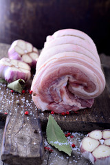 Raw veal meat roast roll on wooden cutting board with garlic