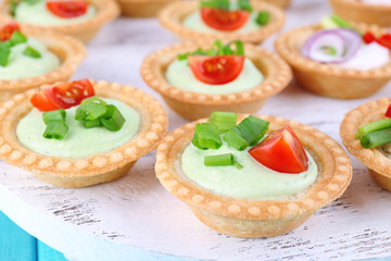 Tartlets with greens and vegetables with sauce on tray close-up