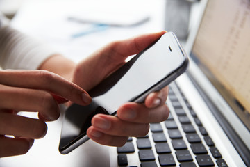 Close Up Of Person At Laptop Using Mobile Phone