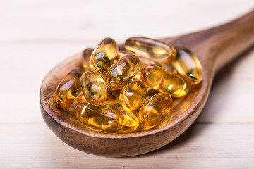 Cod liver oil omega 3 gel capsules isolated on wooden background