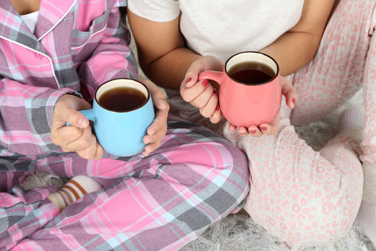 Girls in pajamas drinking tea at home
