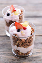 Healthy layered dessert with muesli and berries on table