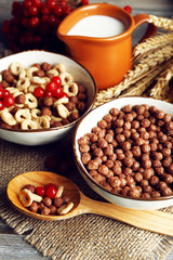 Various sweet cereals in ceramic bowls, fruits and jug with