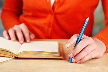 Female hand with pen and diary at wooden desktop